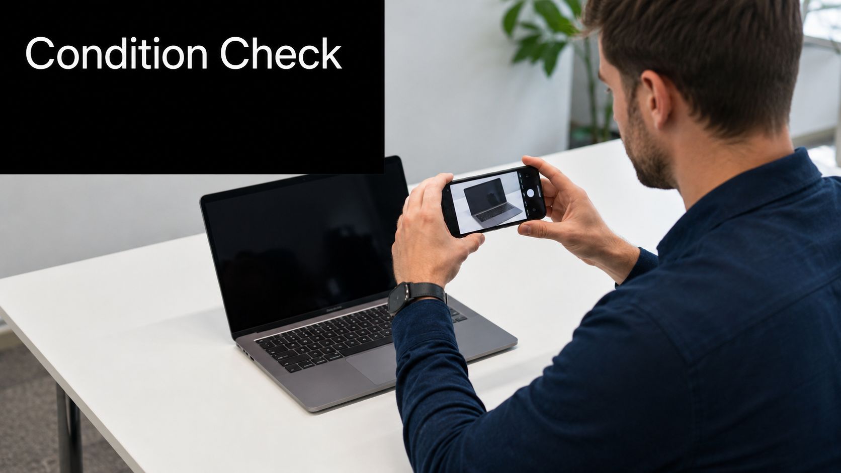 A man taking a photograph of his laptop screen with a smartphone to document equipment condition.