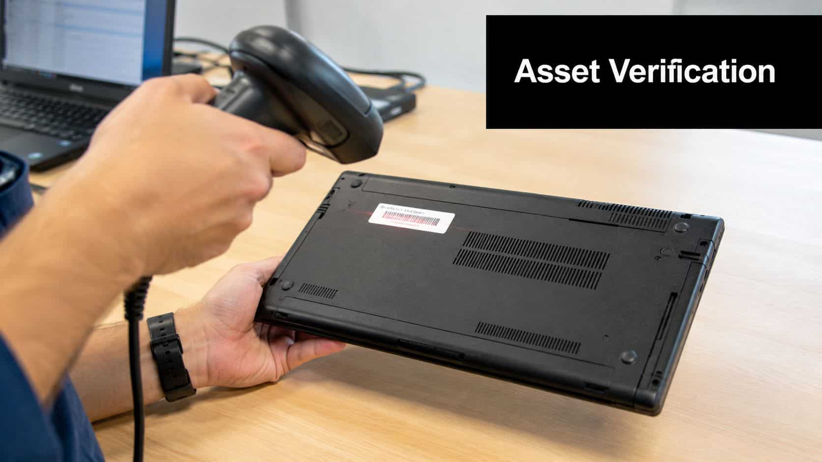 An IT technician scans a barcode on the bottom of a black laptop for asset verification.