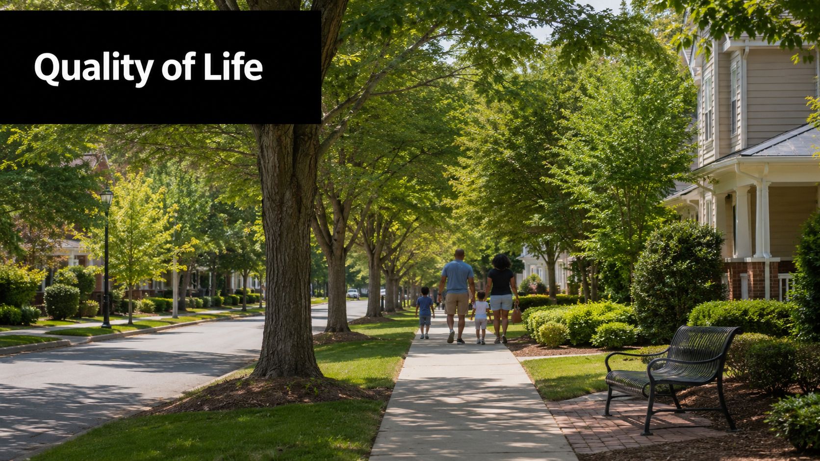 A family of four walking along a sunlit residential sidewalk lined with mature trees and suburban houses.